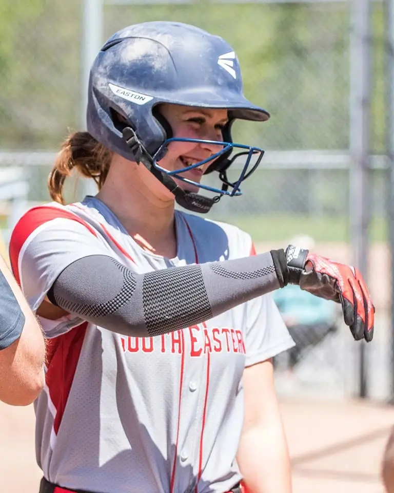 A smiling SEO batter in her helmet holding out a fist bump.